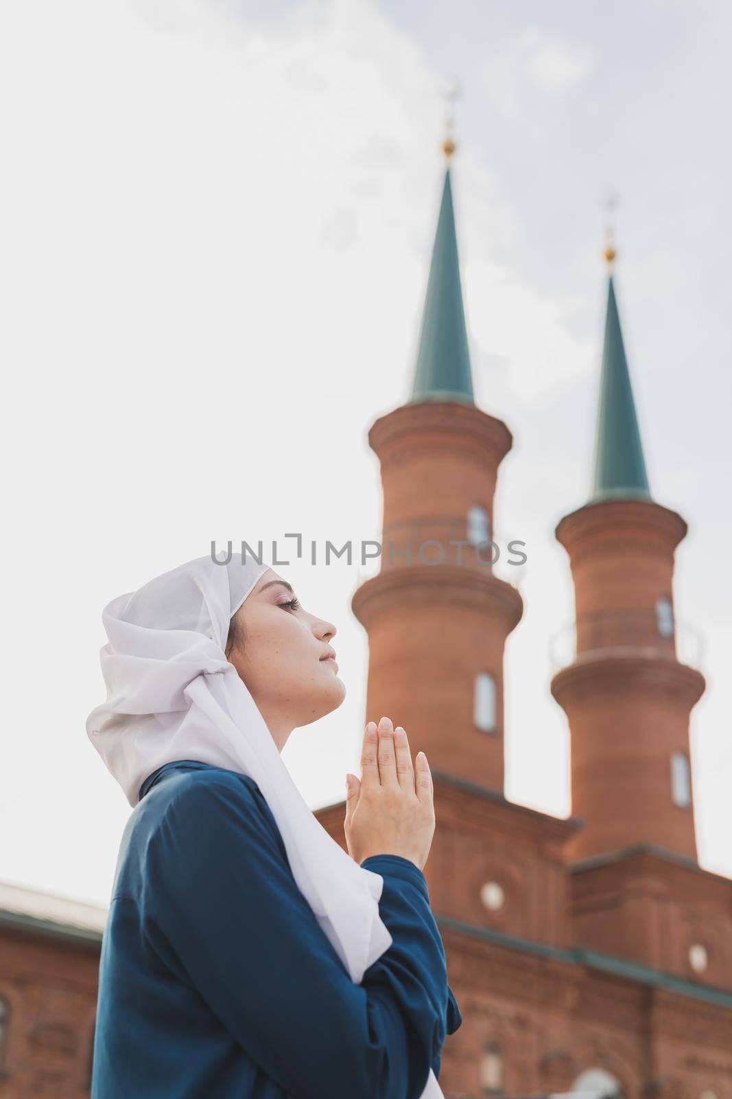Young Muslim woman prayer wear hijab fasting pray to allah on mosque background
