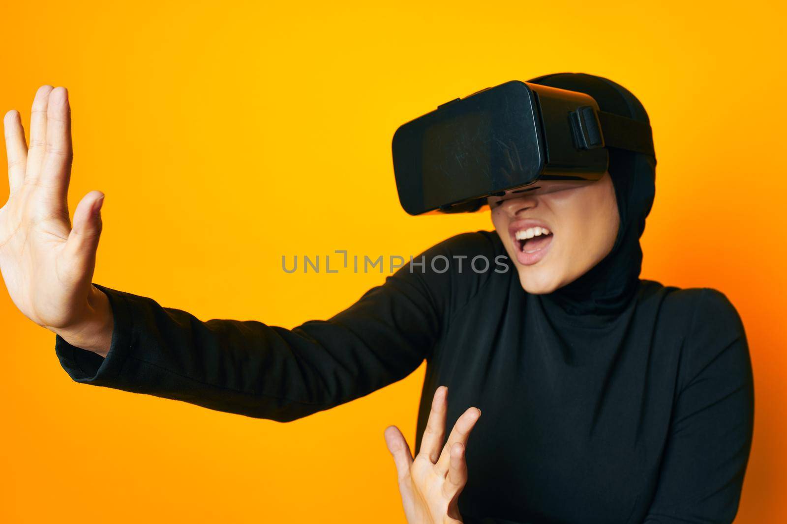 cheerful woman in black hijab VR glasses emotions studio lifestyle. High quality photo