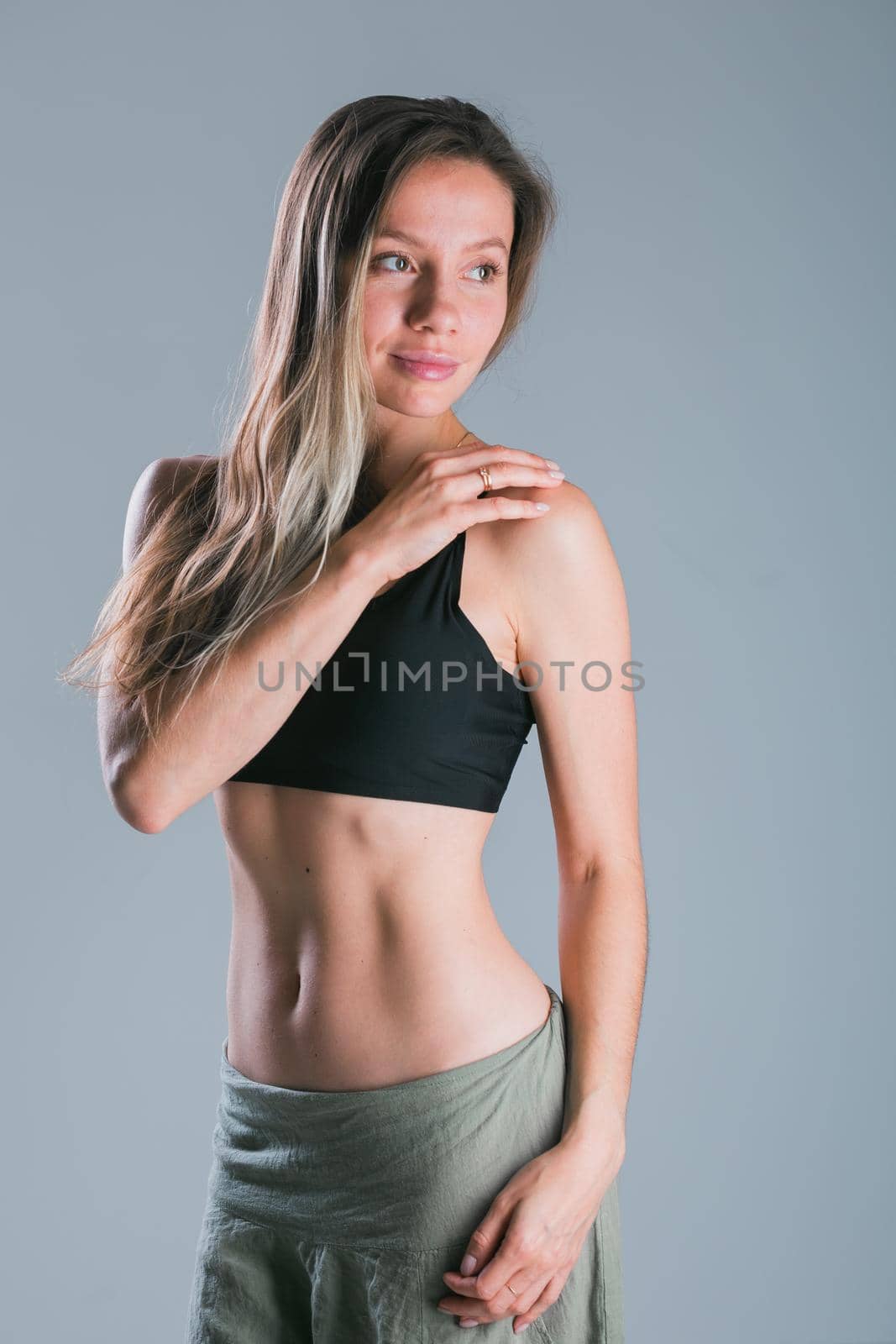 Fitness and diet concept. Portrait of young woman with perfect sporty body and pretty flat abs in sexy sportswear top on gray background