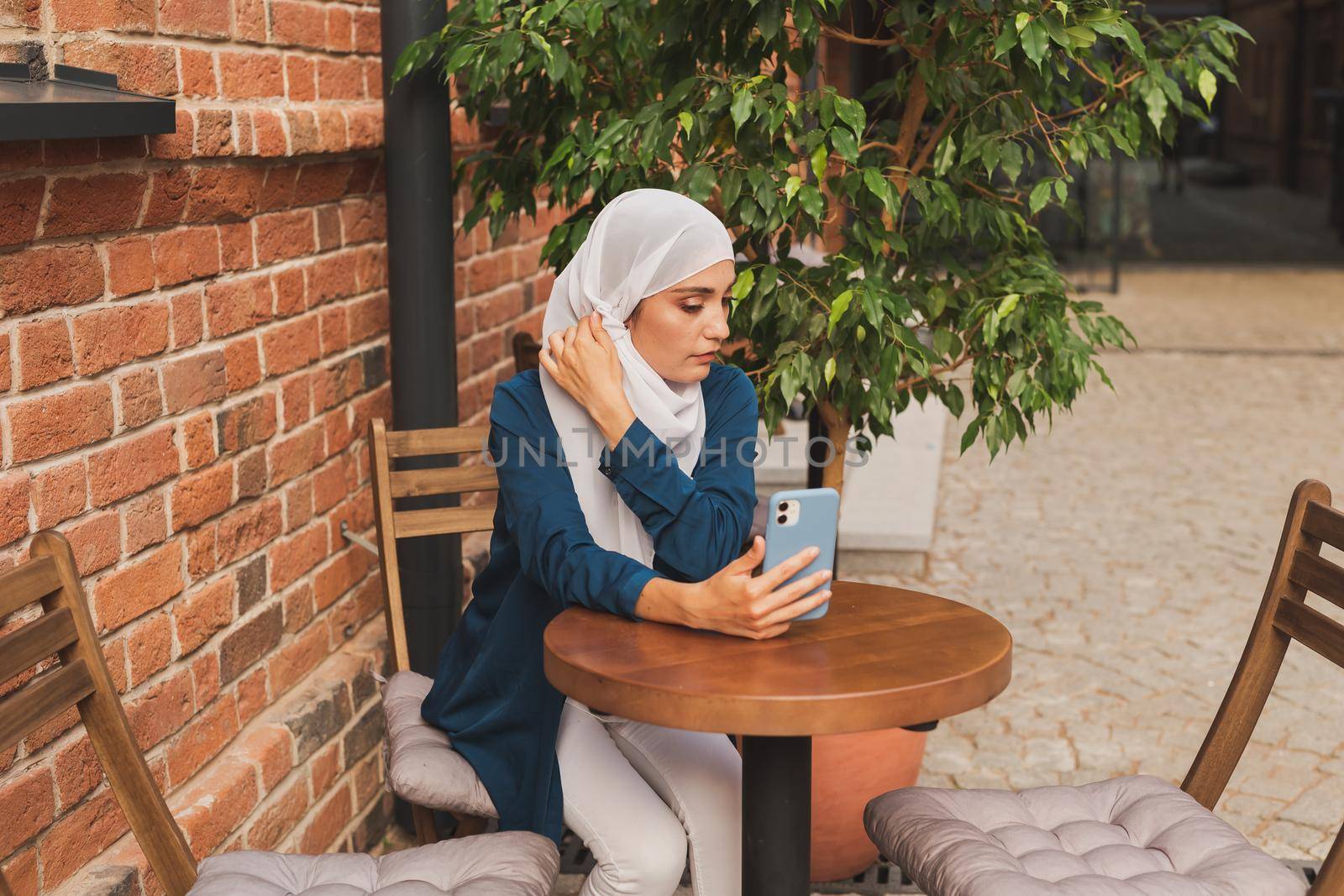 Happy muslim woman having video call on smartphone in city.