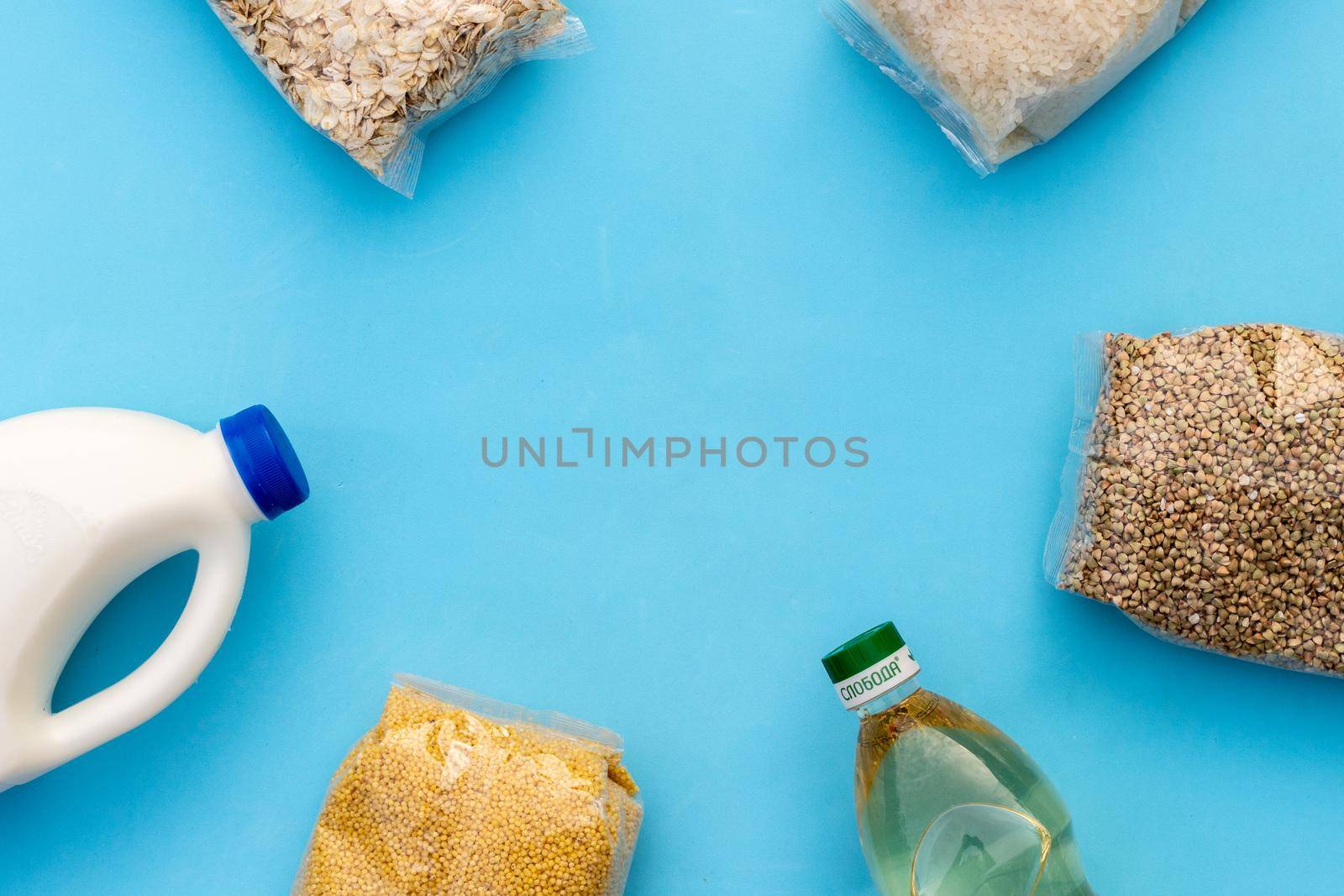 Food supply. Raw porridge, cereals, milk and vegetable oil on the blue table. Copy of space, flat. Food security for the poor by Matiunina