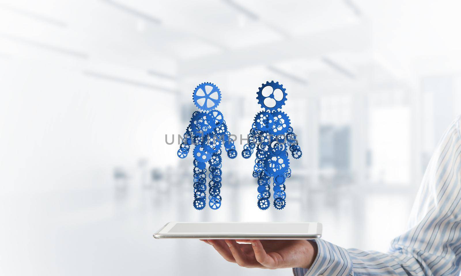 Close of businessman holdingn tablet pc with figures of man and woman made of gears. Mixed media