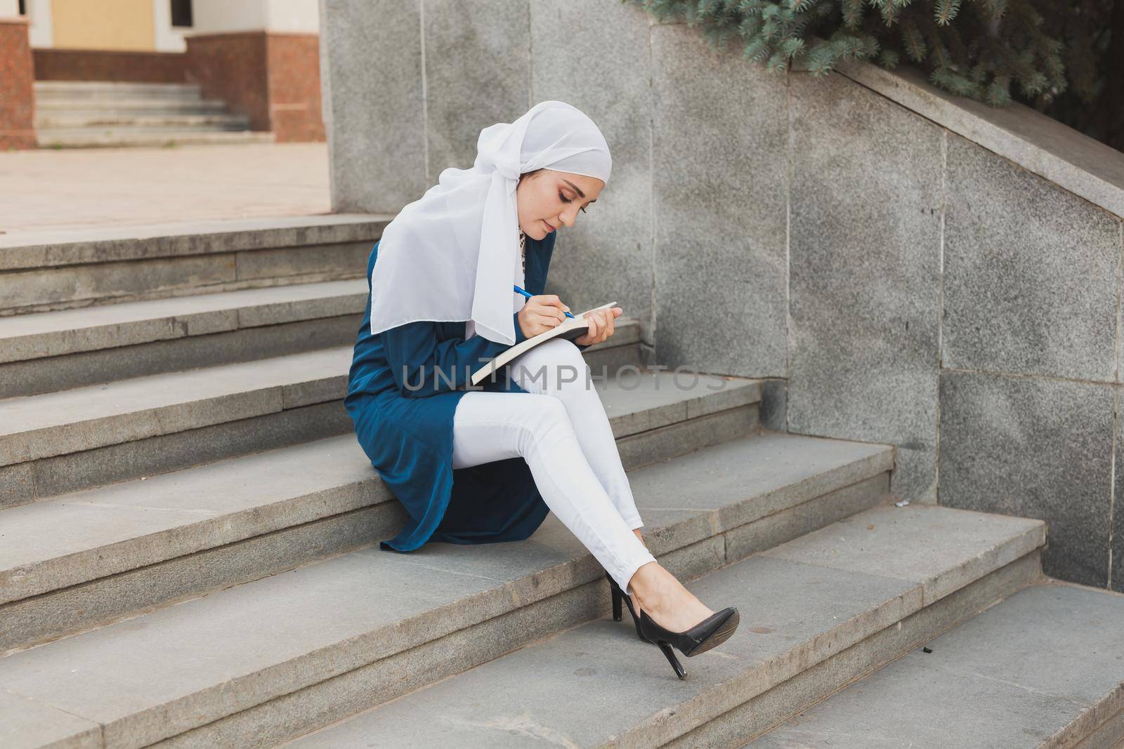 Arab female student sitting on stairs in downtown