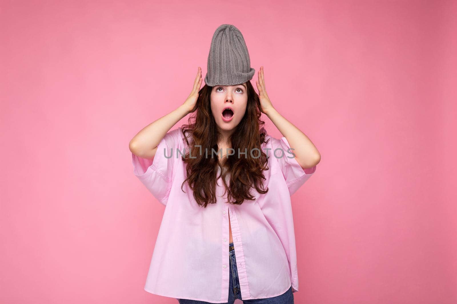 Attractive shocked amazed young brunette woman standing isolated over colorful background wall wearing everyday stylish outfit showing facial emotions looking at camera by TRMK