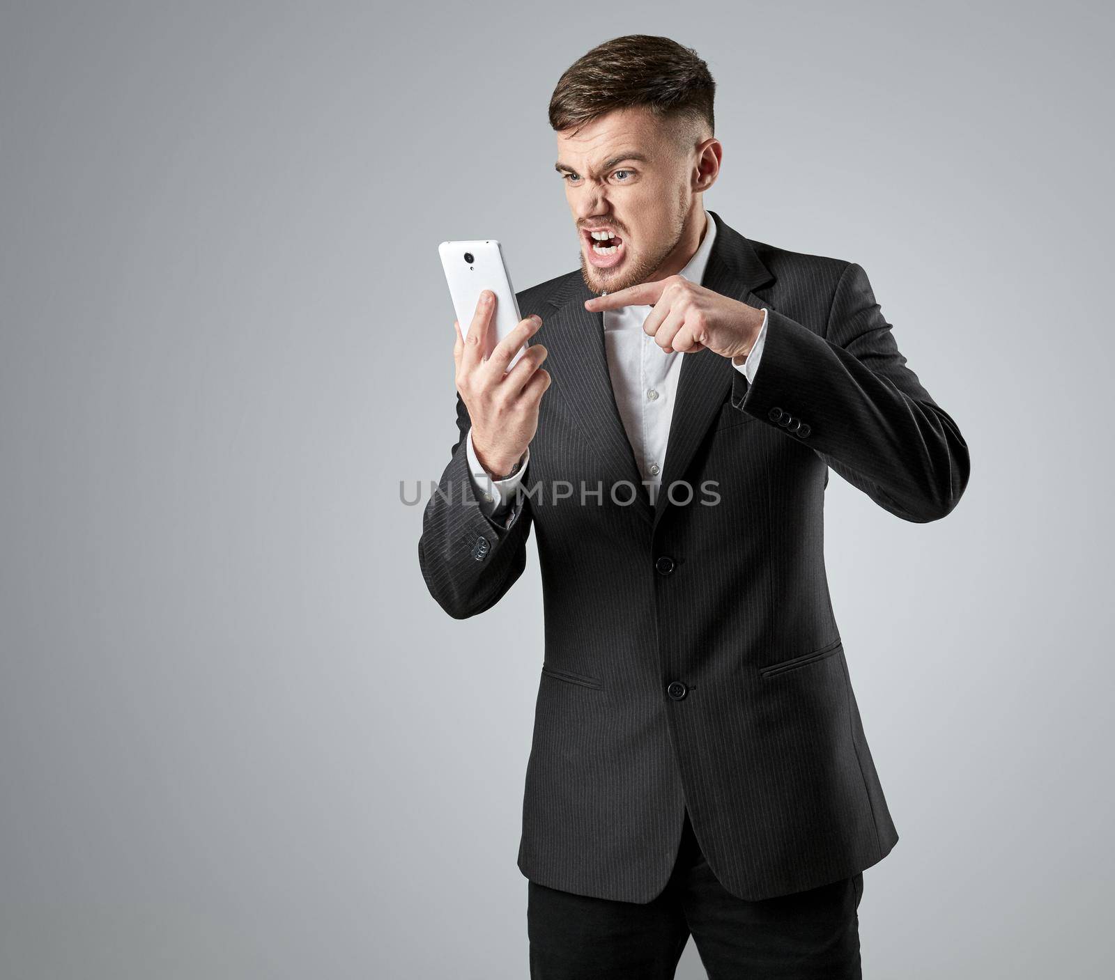 Portrait of a handsome businessman making a phone call against a grey background. Emotions