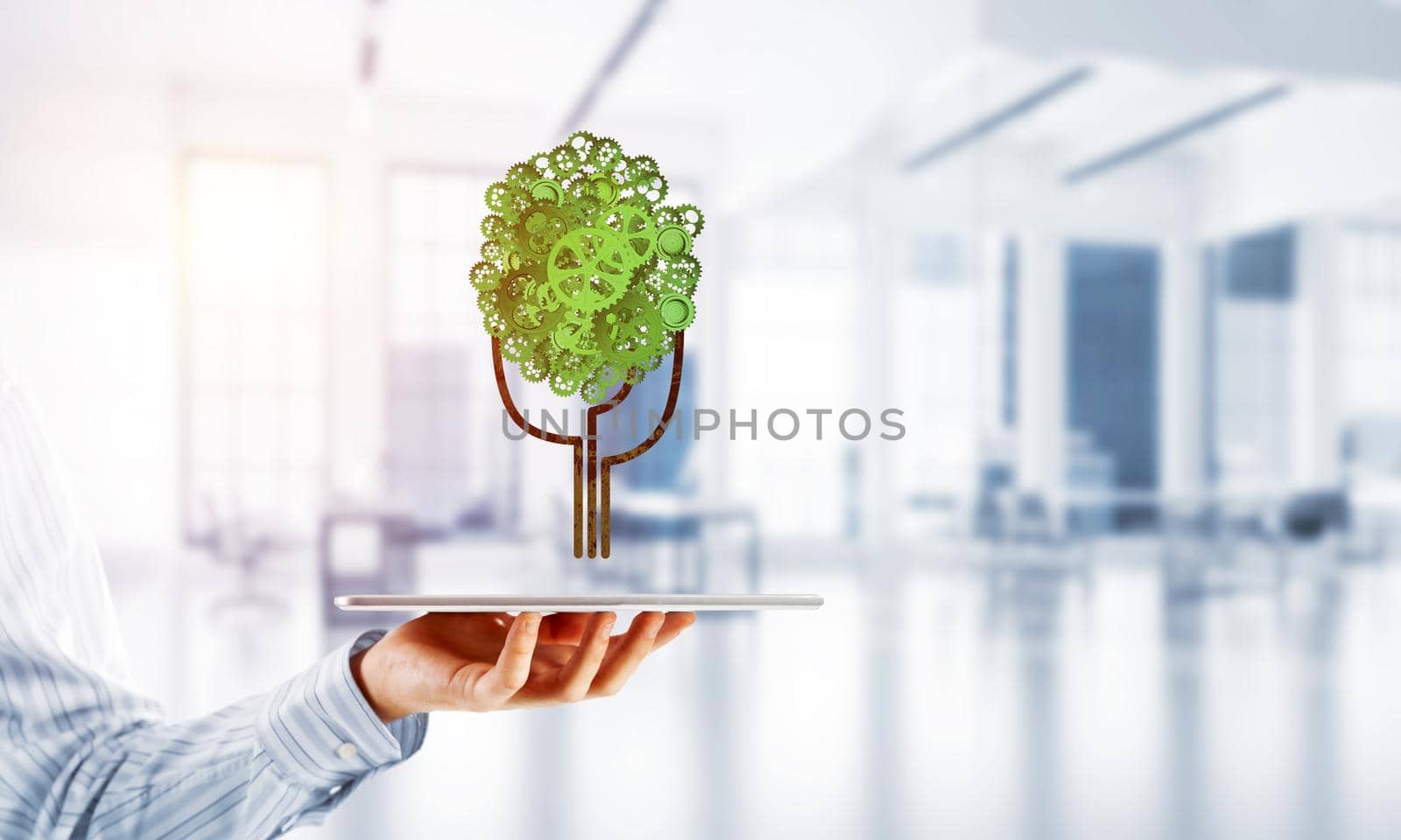 Close of businessman holding tablet pc with green tree made of gears and cogwheels. Mixed media