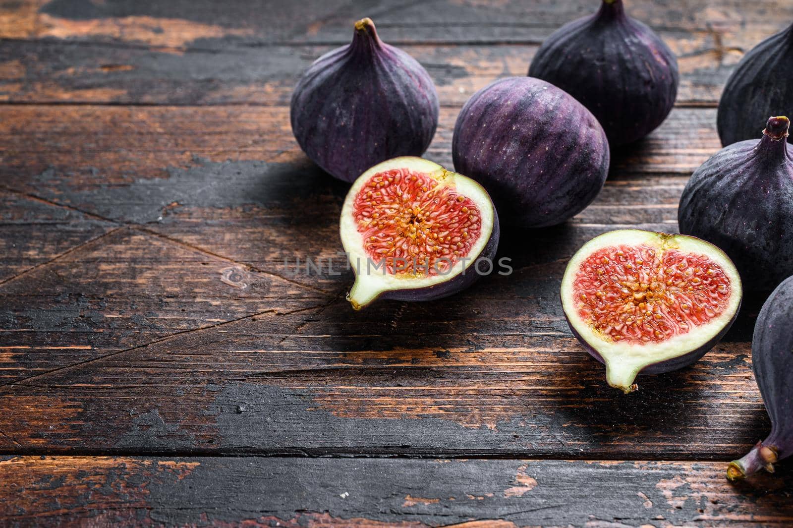 Purple figs on a wooden table. Dark wooden background. Top view. Copy space.