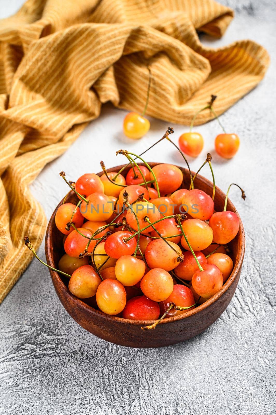 Mix of yellow and red ripe cherries in a bowl. White background. Top view by Composter