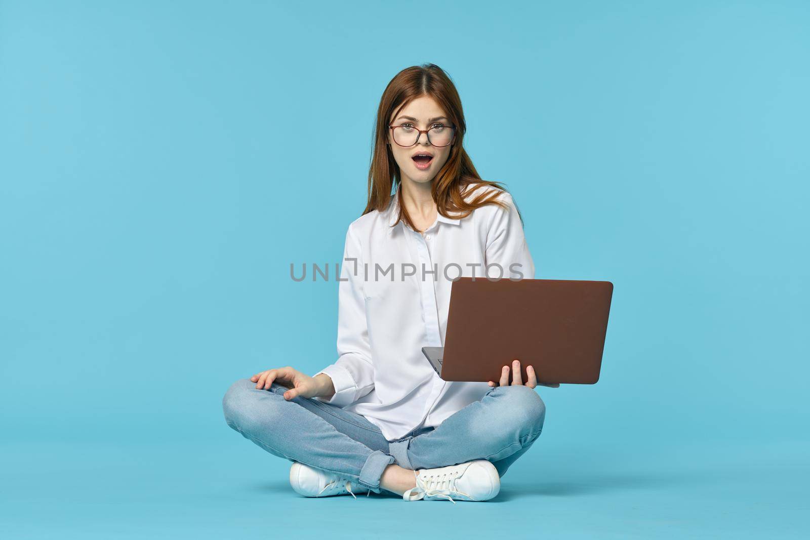 woman with laptop learning internet online education blue background. High quality photo