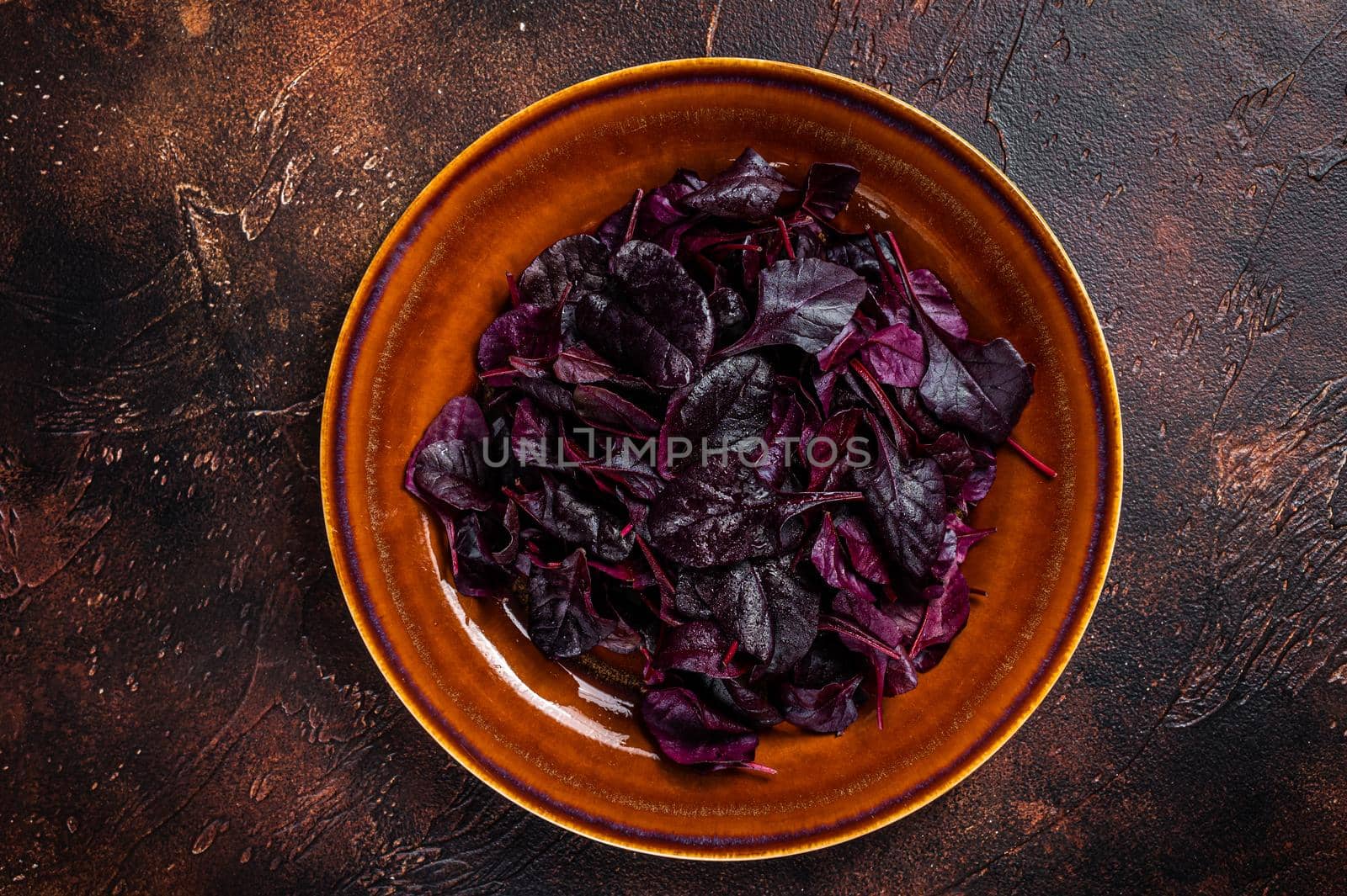 Raw Ruby or red chard salad Leafs on a rustic plate. Dark background. Top view.