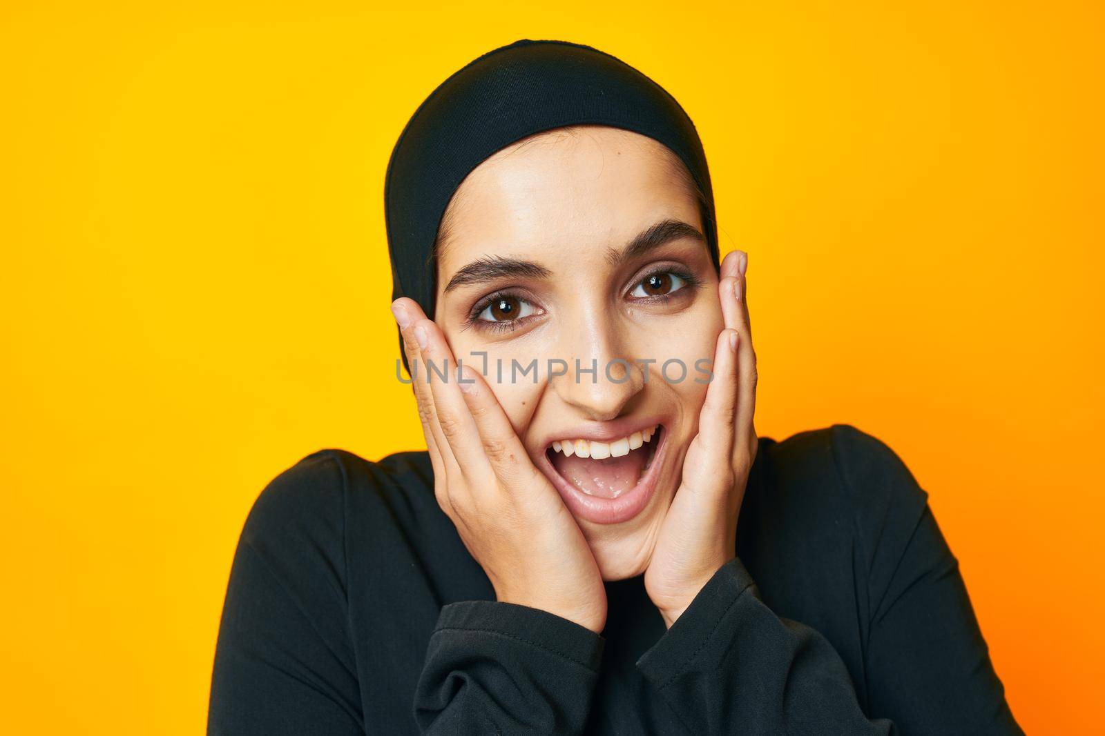 Muslim in black hijab posing fashion hand gesture yellow background. High quality photo