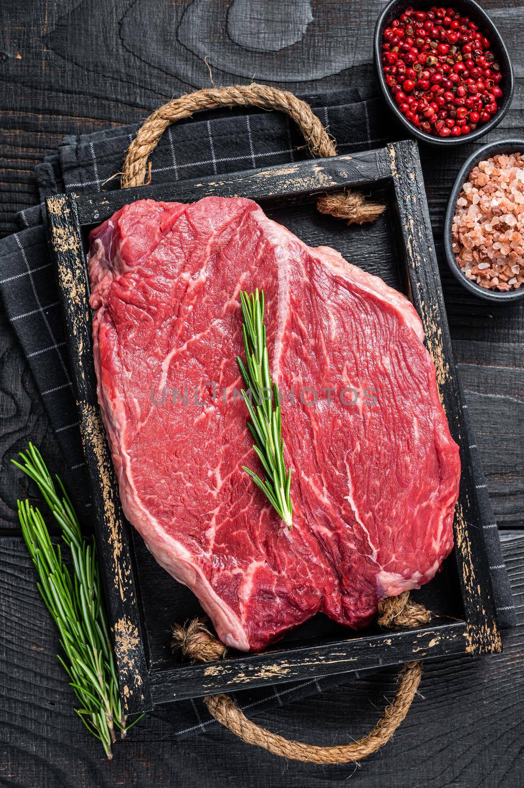 Beef raw fillet for steaks in a wooden tray with herbs. Black wooden background. Top view by Composter