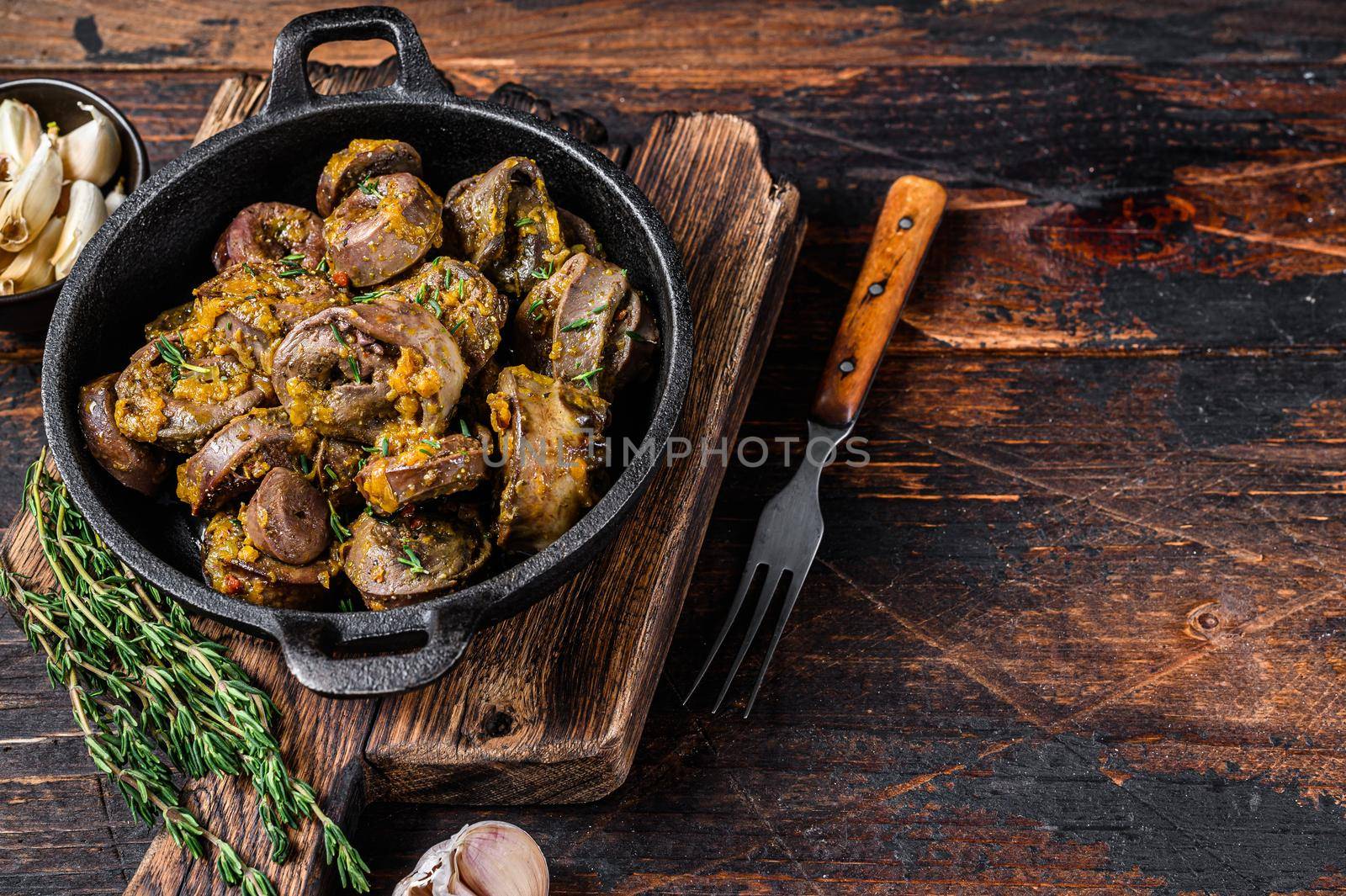 Cooked turkey hearts offals with herbs. Dark wooden background. Top view. Copy space.