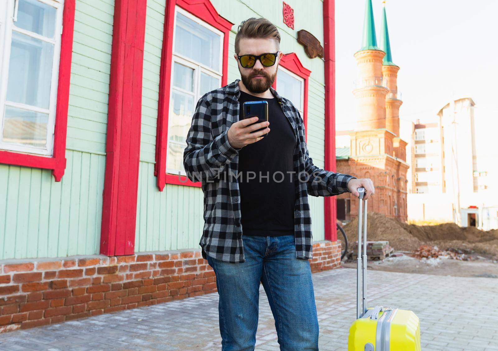 Full body side portrait of happy travel man with suitcase walking along the building in city