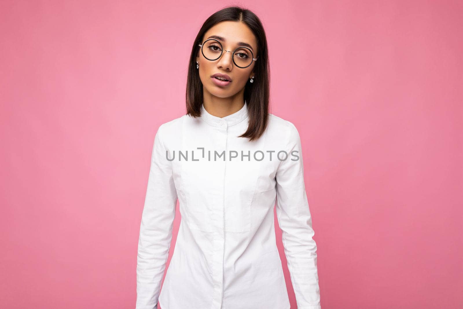 Attractive upset young brunette woman wearing everyday stylish clothes and modern optical glasses isolated on colorful background wall looking at camera.
