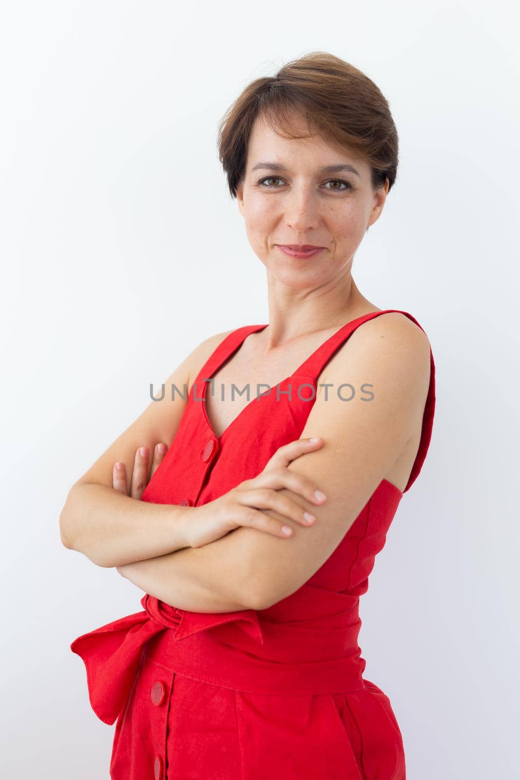 Confident business woman wearing red dress standing with crossed arms. Isolated portrait