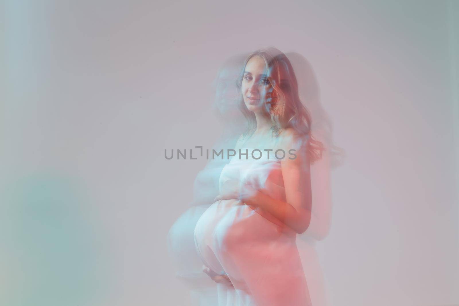 Elegant pregnant young woman standing wearing light fabric. Pregnancy, fantasy and fairy tale.