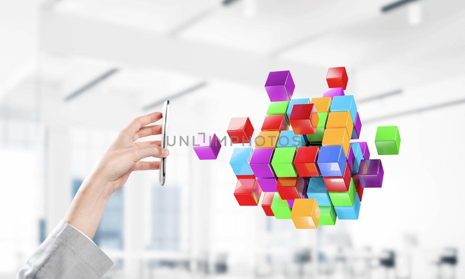 Close of businessman hand holding smartphone and cube figure out of screen. Mixed media