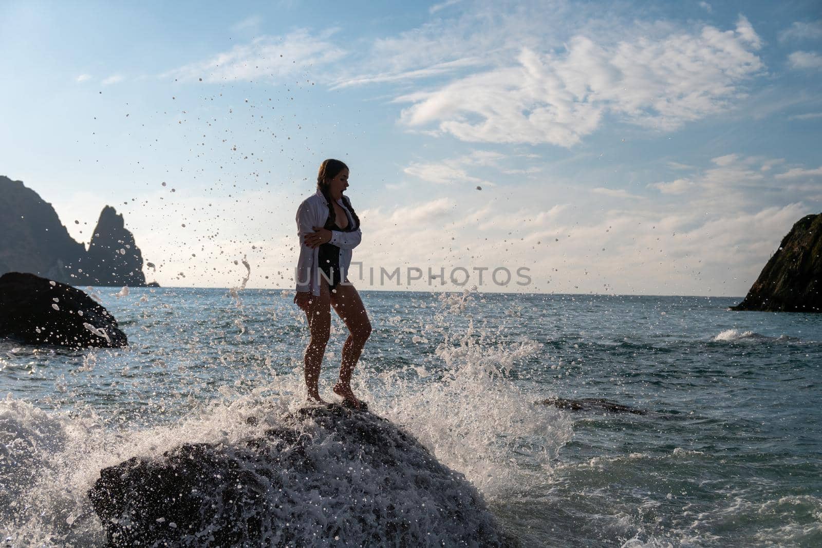Selective focus. Happy carefree sensual woman with long hair in black swimwear posing at sunset beach. Silhouette of young beautiful playful positive woman outdoor. Summer vacation and trip concept.