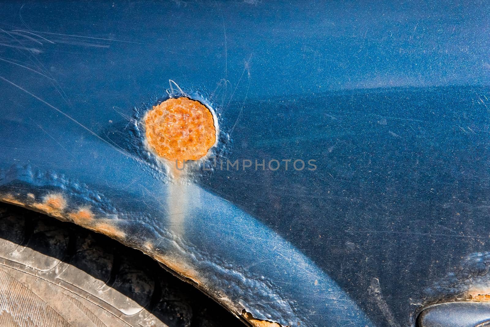 Rust on the wing of a wear old dirty car, close-up. Corrosion metal surface.