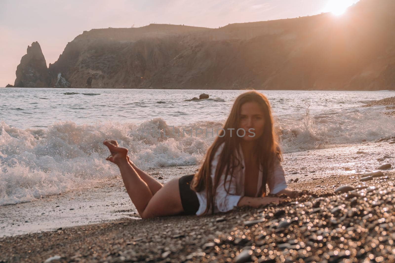 Selective focus. Happy carefree sensual woman with long hair in black swimwear posing at sunset beach. Silhouette of young beautiful playful positive woman outdoor. Summer vacation and trip concept.