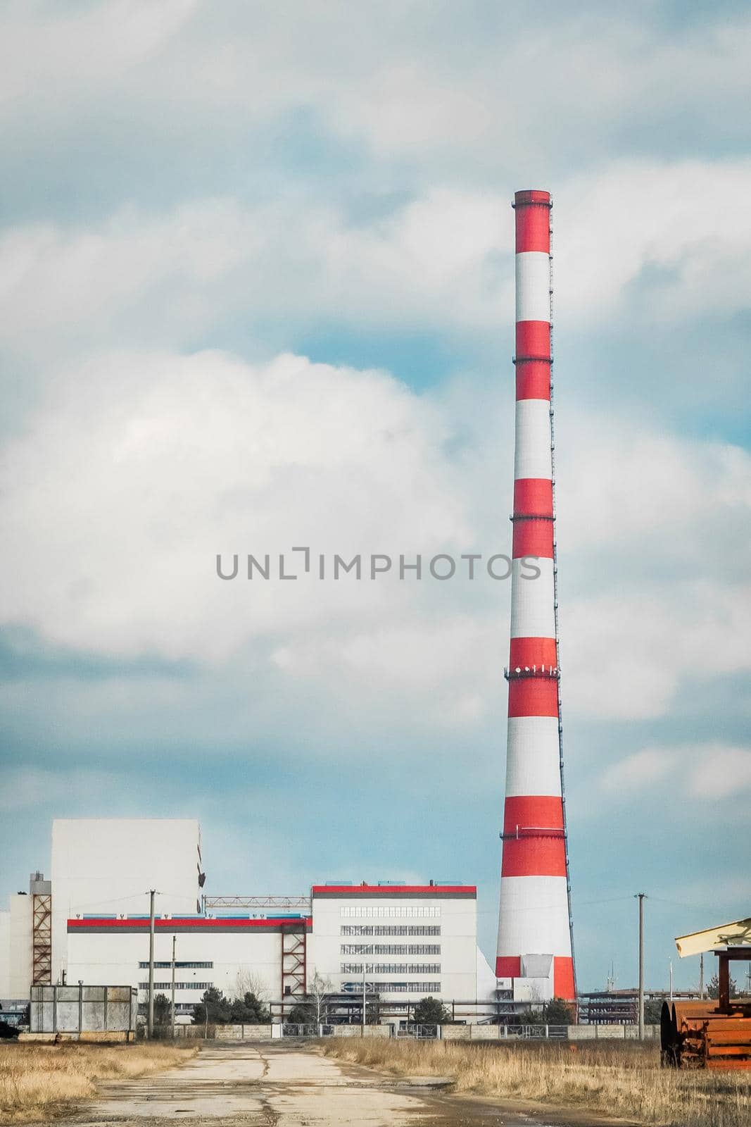 Industrial zone, construction outdoor site of a thermal power plant with chimney on a background of cloudy sky.