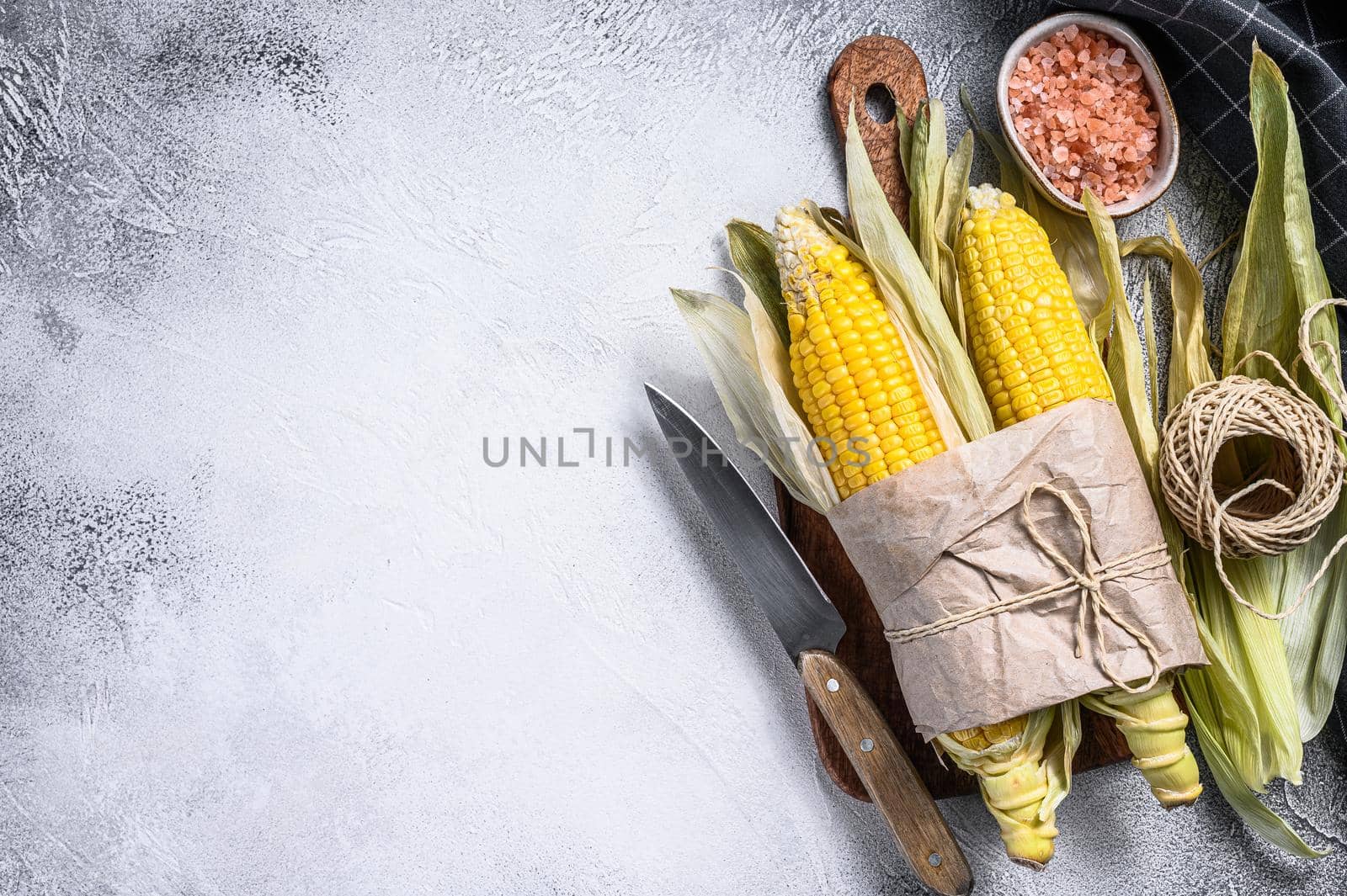 Raw corn on cobs on rustic table. Gray background. Top view. Copy space.