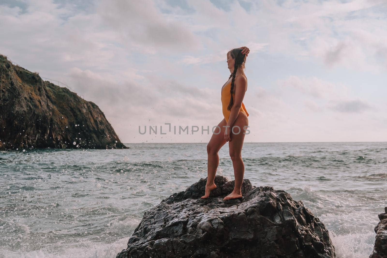 Selective focus. Happy carefree sensual woman with long hair in black swimwear posing at sunset beach. Silhouette of young beautiful playful positive woman outdoor. Summer vacation and trip concept.