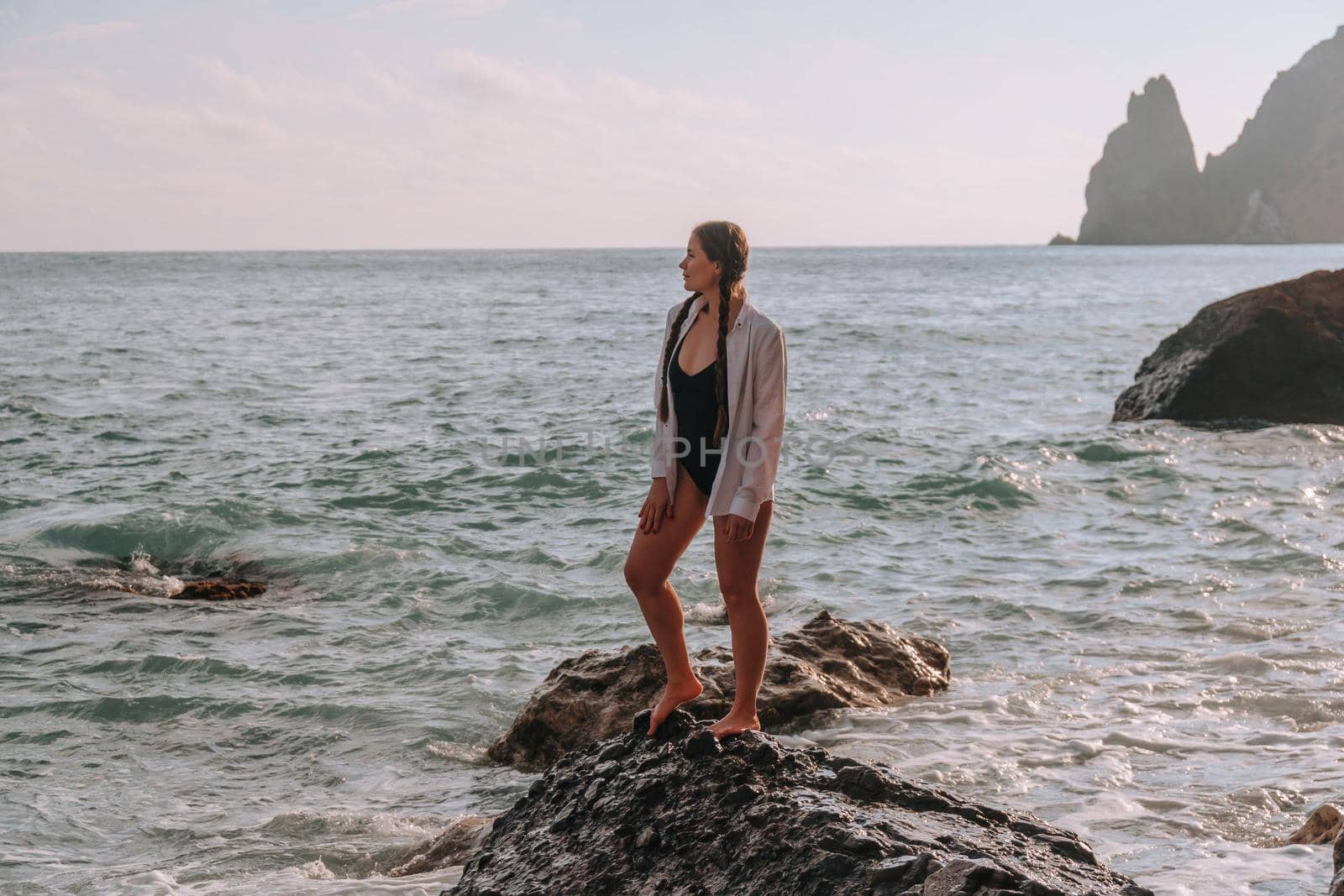 Selective focus. Happy carefree sensual woman with long hair in black swimwear posing at sunset beach. Silhouette of young beautiful playful positive woman outdoor. Summer vacation and trip concept.