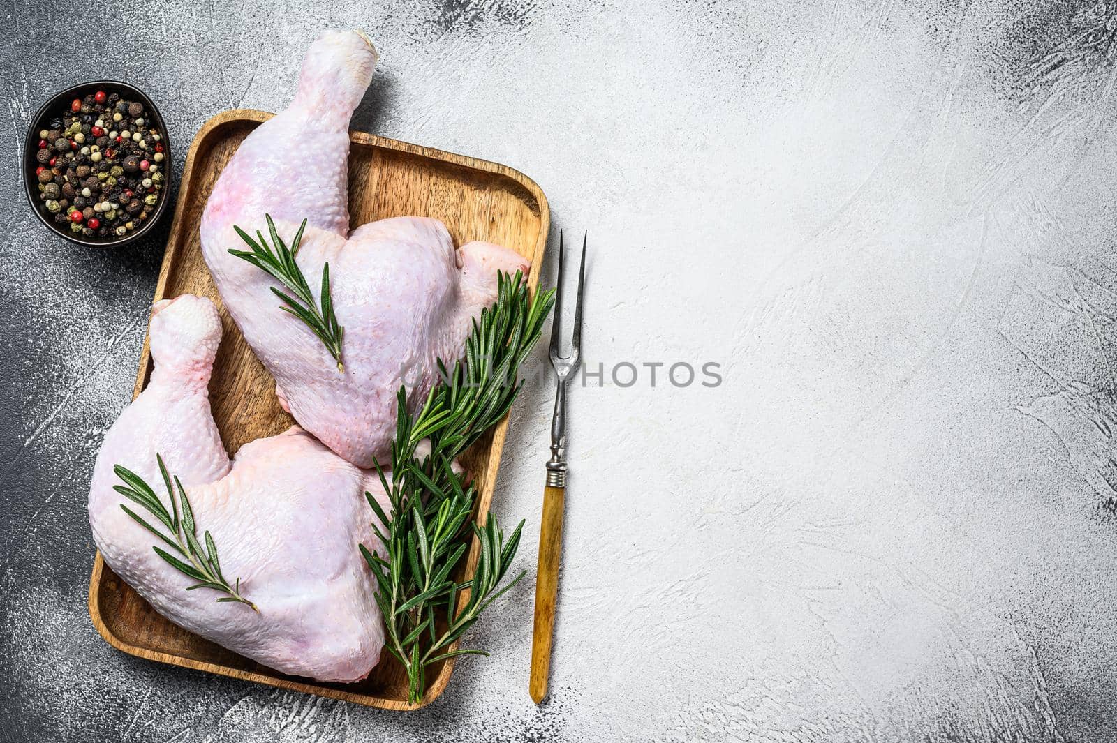 Raw chicken legs on a cutting board. White background. Top view. Copy space.