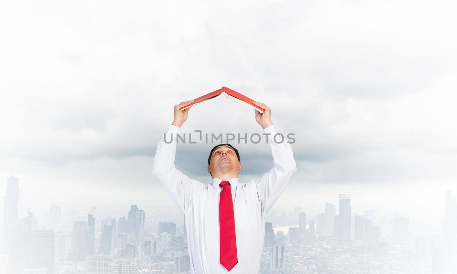 Senior businessman holding open diary overhead as roof. Man in white shirt and tie standing on cloudy cityscape background. Education and professional knowledges. Time management and day planning.