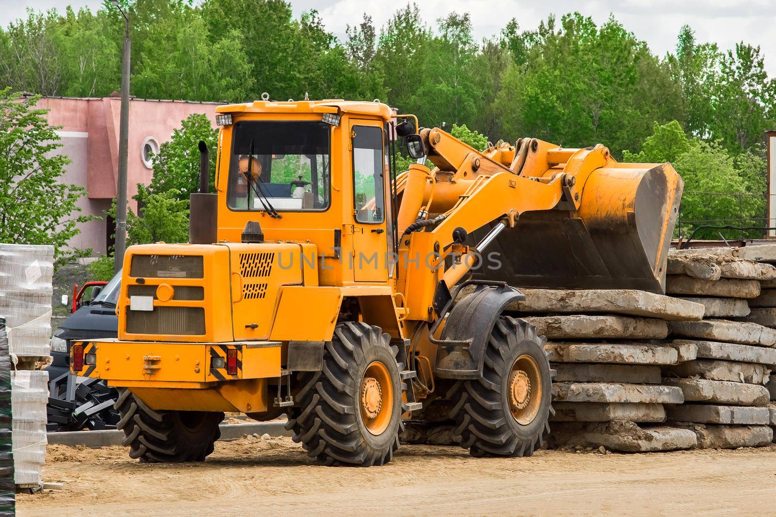 Bulldozer or excavator industrial heavy machine at a construction site unloads old concrete stone slabs material by AYDO8