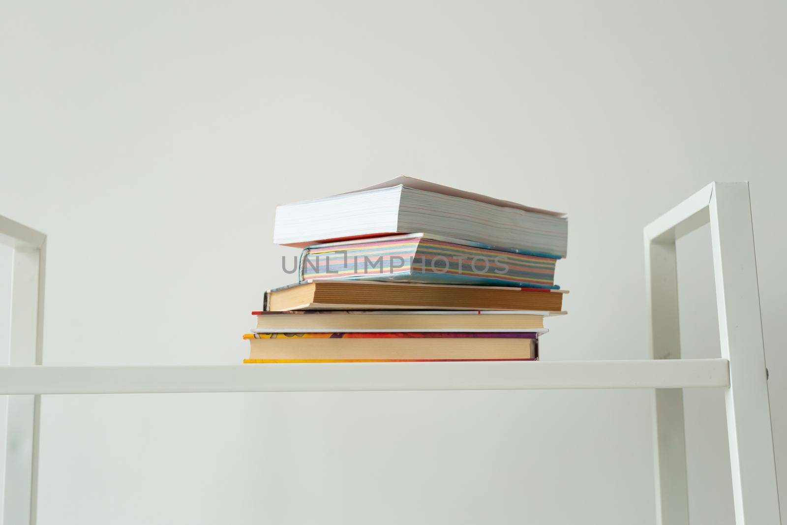 Books standing on a white rack at home. Knowledge, study and literature