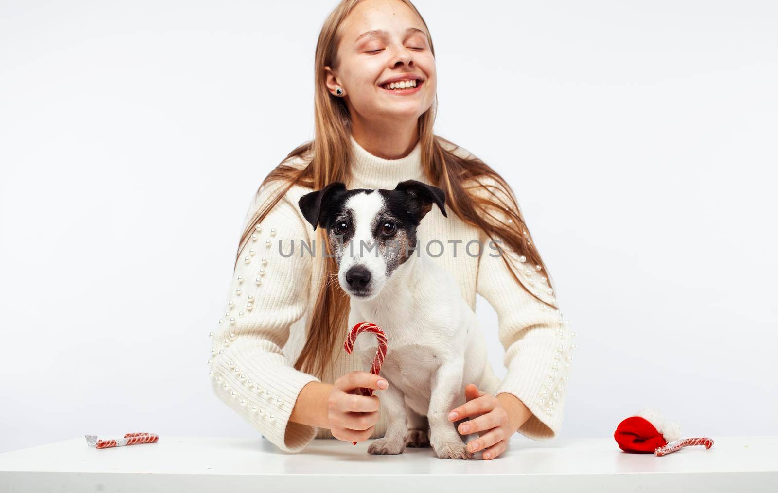 pretty young blond girl with her little cute dog wearing Santas red hat at Christmas holiday isolated on white background, lifestyle people concept close up