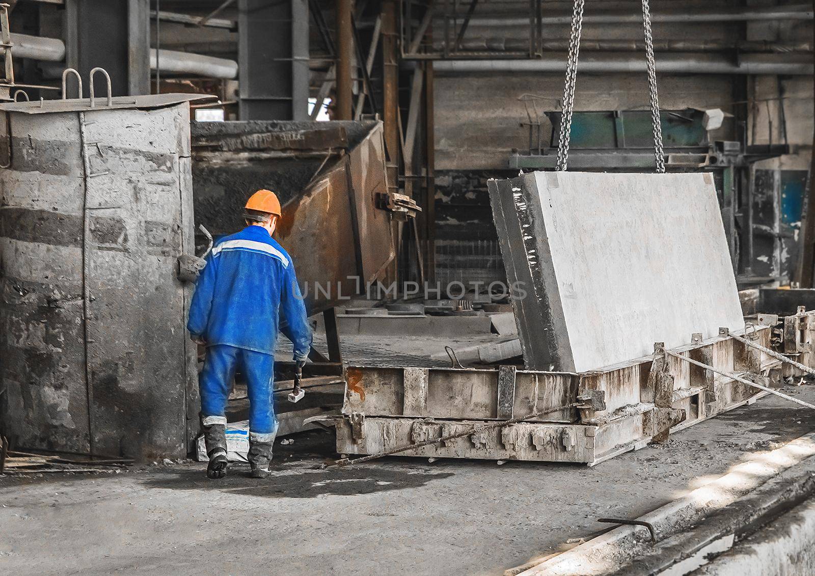 Worker in a reinforcement workshop controls equipment for moving concrete and metal structures.