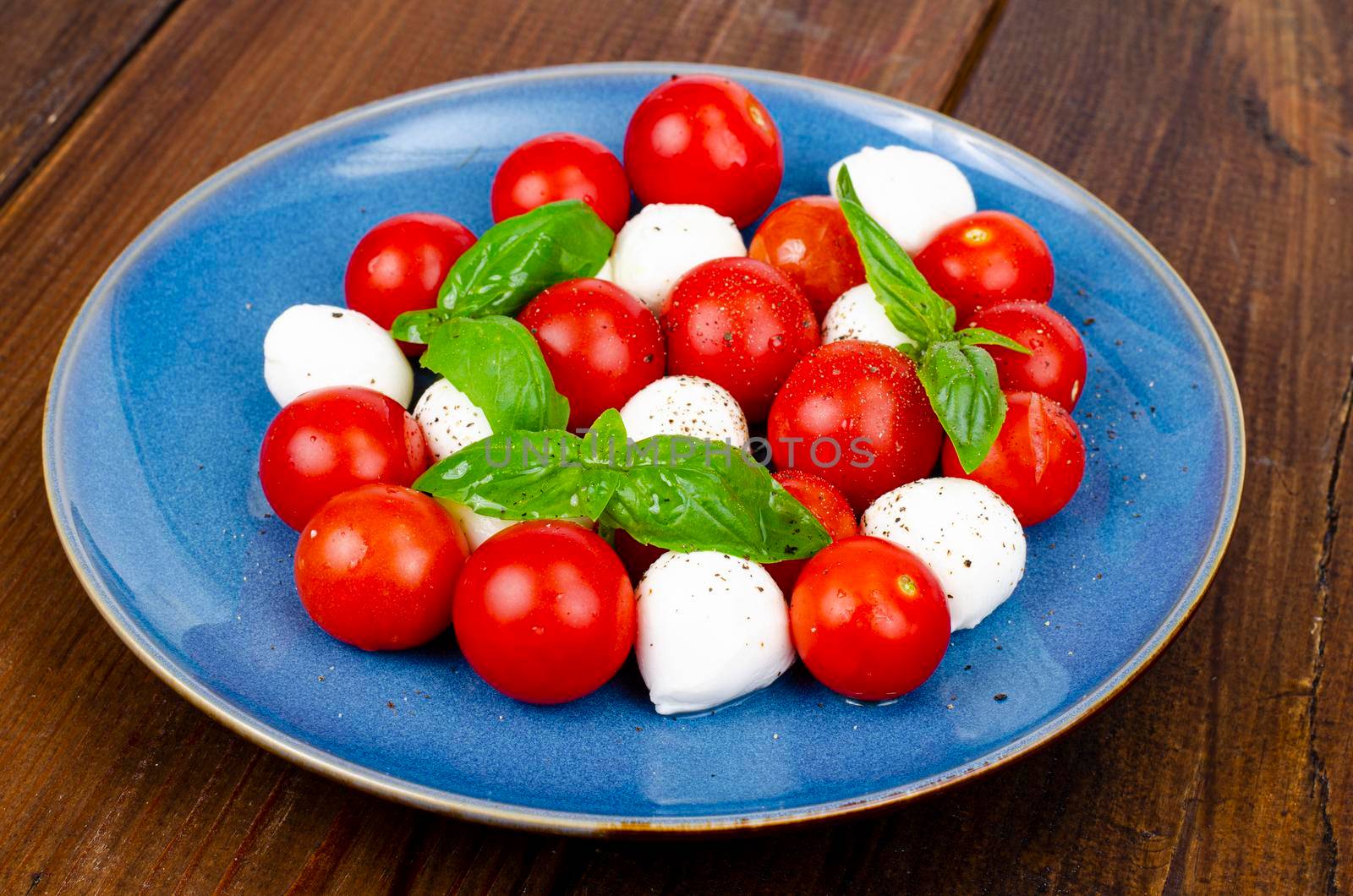 Delicious Italian caprese salad with basil, mozzarella and cherry tomatoes. Studio Photo