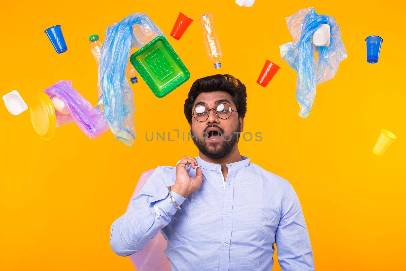 Problem of trash, plastic recycling, pollution and environmental concept - man carrying garbage bag on yellow background.