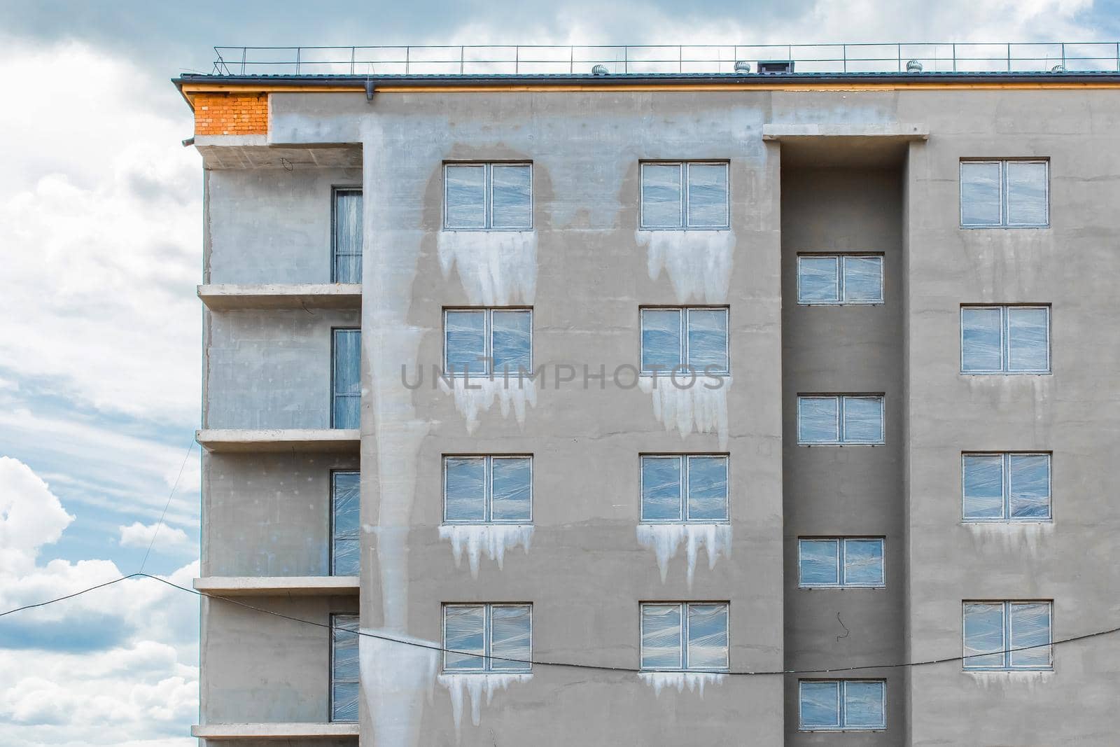 Concrete cement facade with a windows of a new under construction modern city house on a construction site.