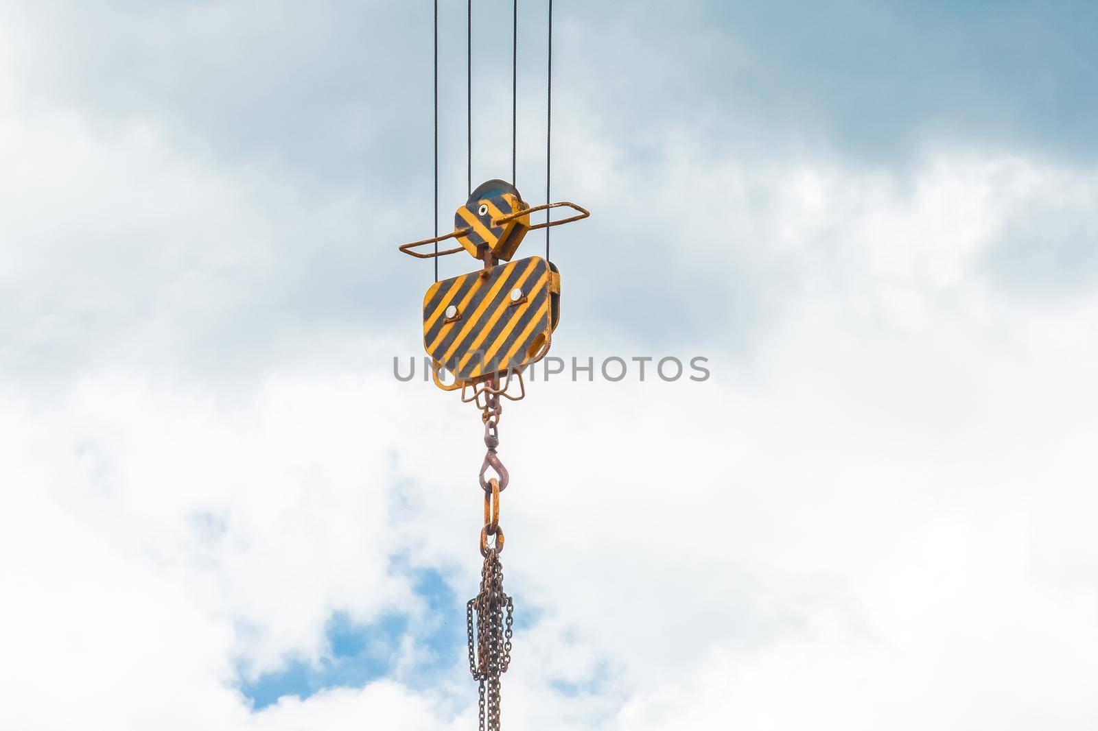 Hoisting heavy equipment lifting mechanism of a tower crane with a hook and chain against the sky. Close-up by AYDO8