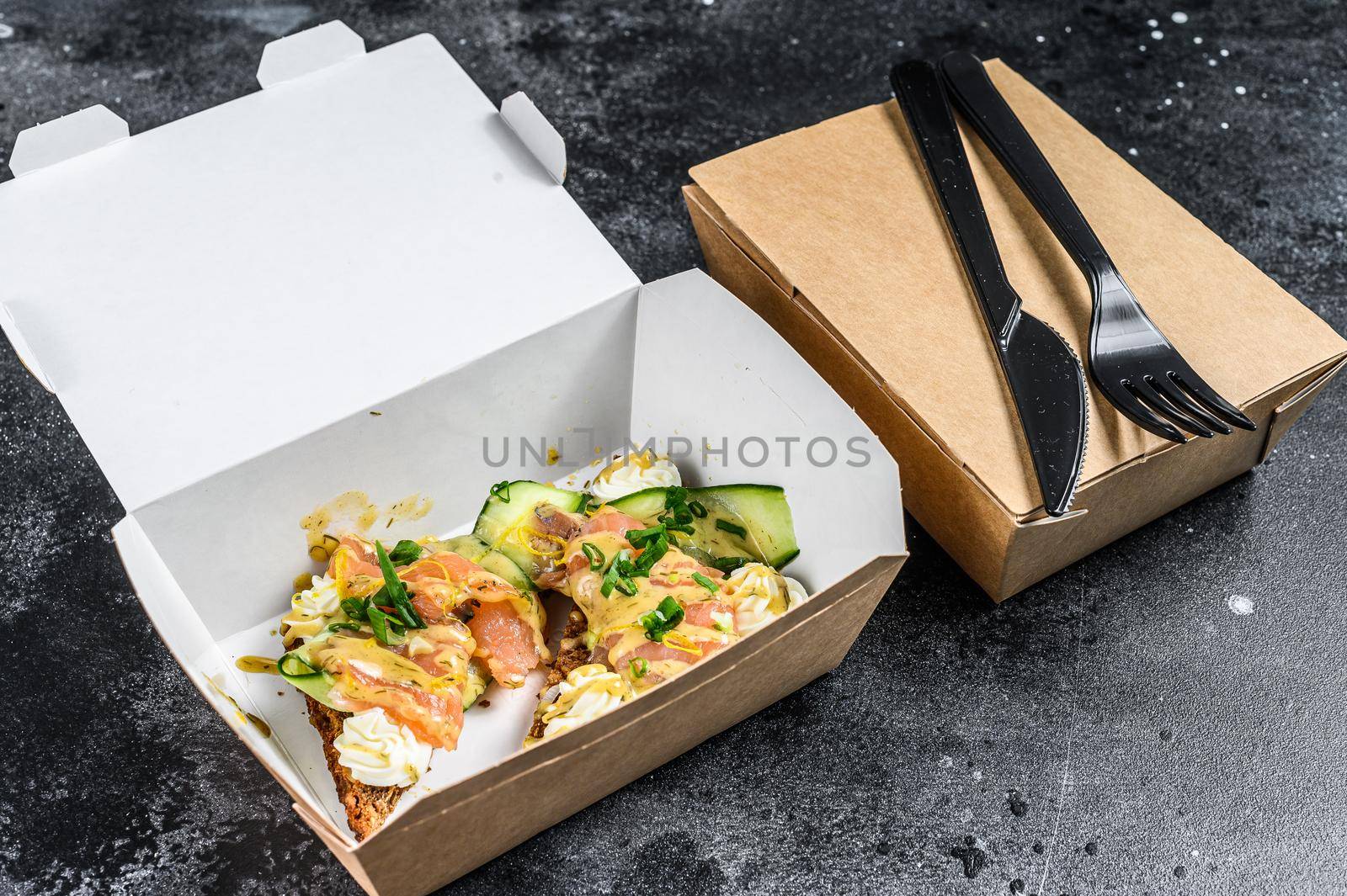 Food delivery paper box for breakfast with sandwich. Black background. Top view by Composter