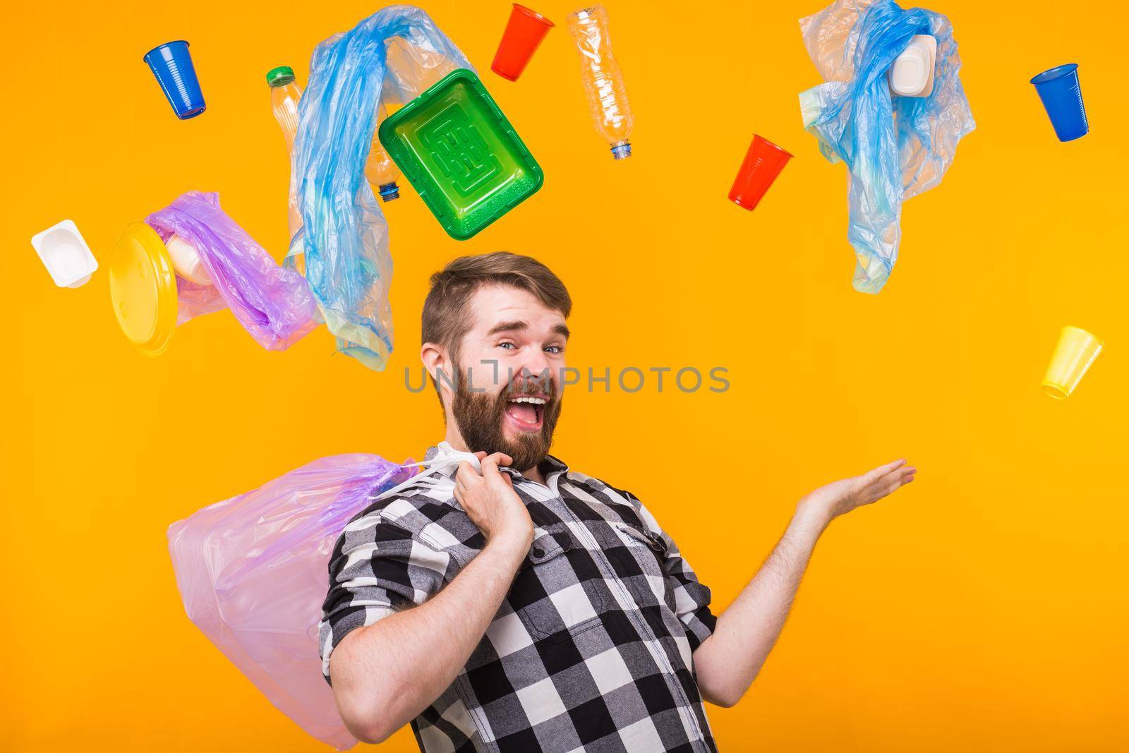 Problem of trash, plastic recycling, pollution and environmental concept - funny man holding garbage for recycling on yellow background