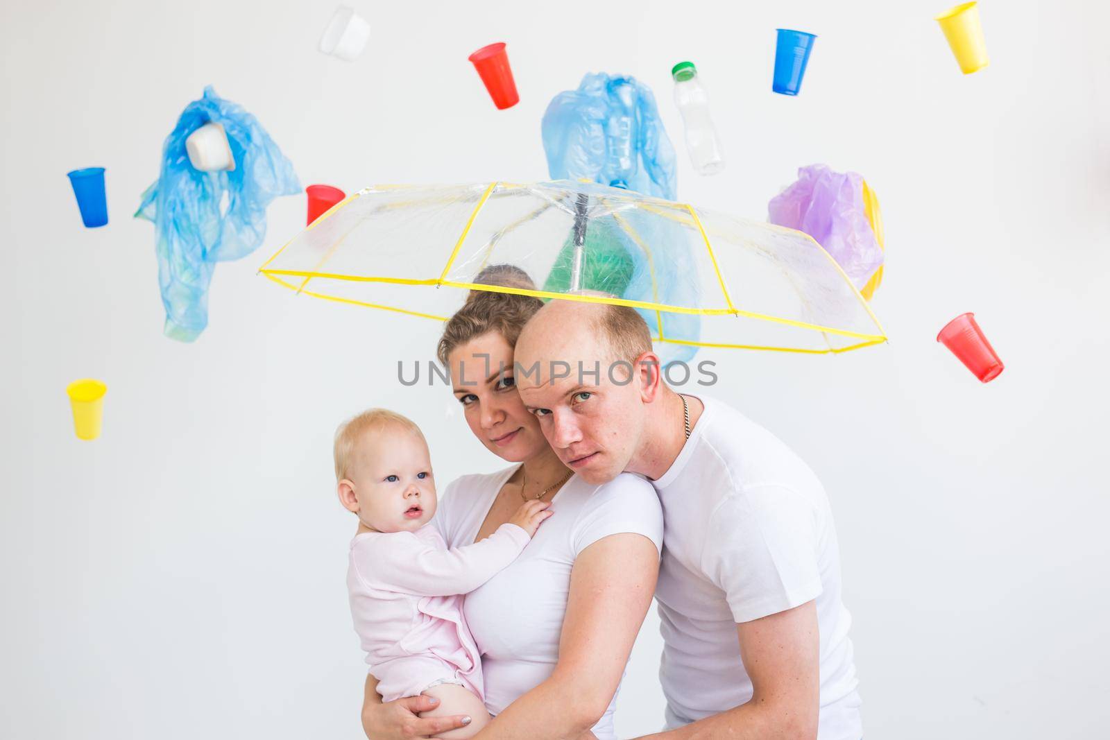 Problem of trash, plastic recycling, pollution and environmental concept - Sad family hiding from garbage under an umbrella on white background.