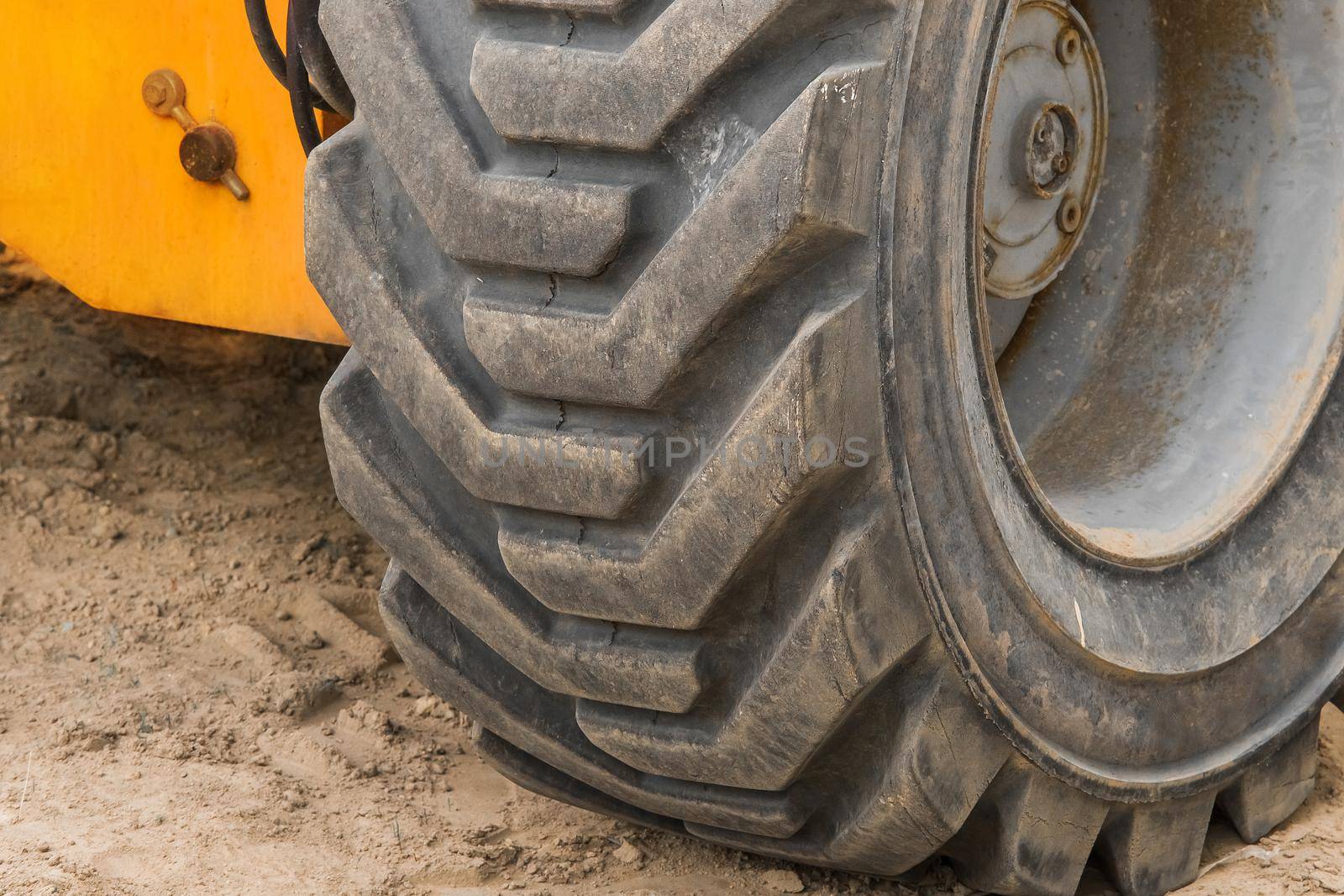 Wheels of industrial lifting transport tire truck against the background of sand at a construction site.