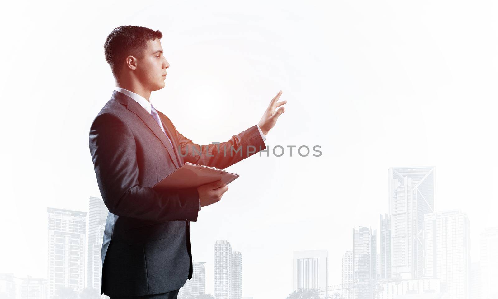 Side view of manager in business suit and tie on background foggy cityscape. Confident businessman standing and pointing copy space. Financial specialist with raised hand promotion mockup.