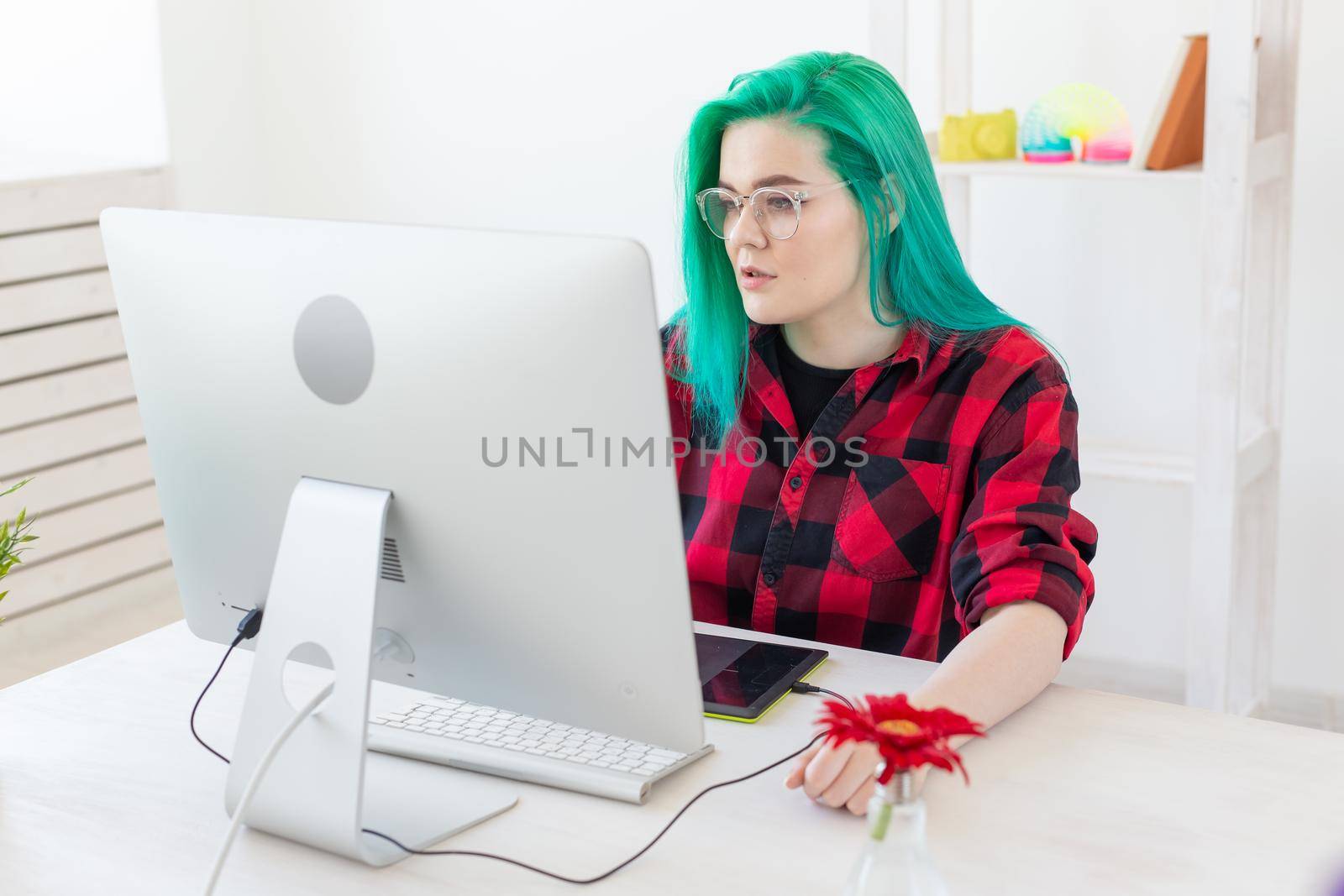 Illustrator, graphic designer, animator and artist concept - creator woman with beautiful green hair and glasses drawing in laptop.
