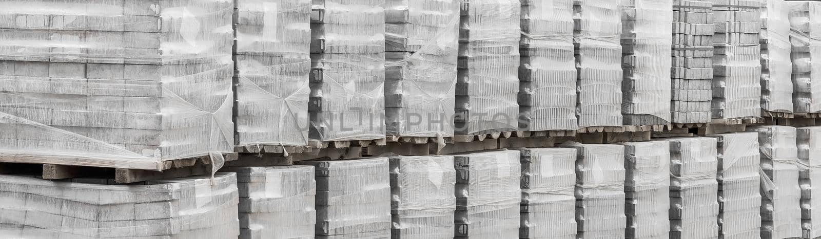 Large pile of packaged paving stone slabs industrial material on pallets at construction site by AYDO8