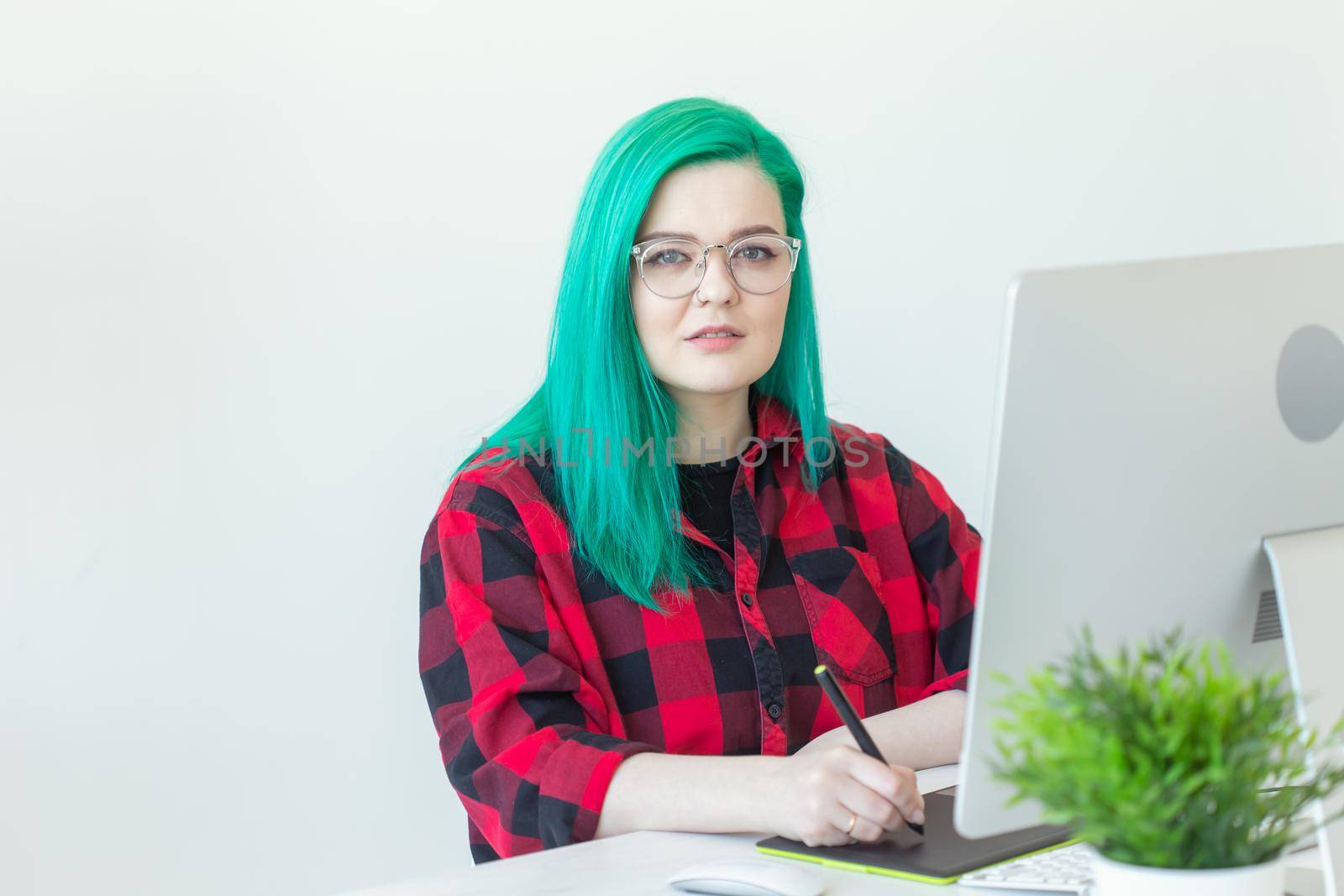 Graphic designer, animator and illustrator concept - young woman with green hair working at the laptop.
