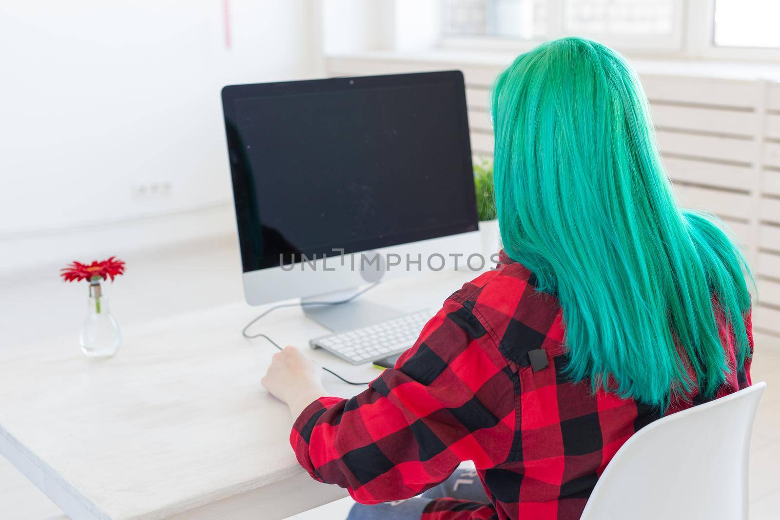 Illustrator, graphic designer, animator and artist concept - creator woman with beautiful green hair and glasses drawing in laptop.