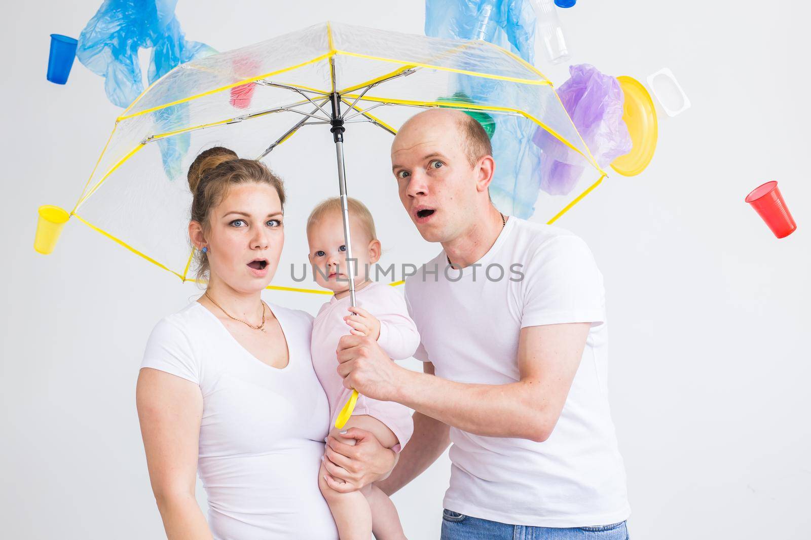 Problem of trash, plastic recycling, pollution and environmental concept - Sad family hiding from garbage under an umbrella on white background.