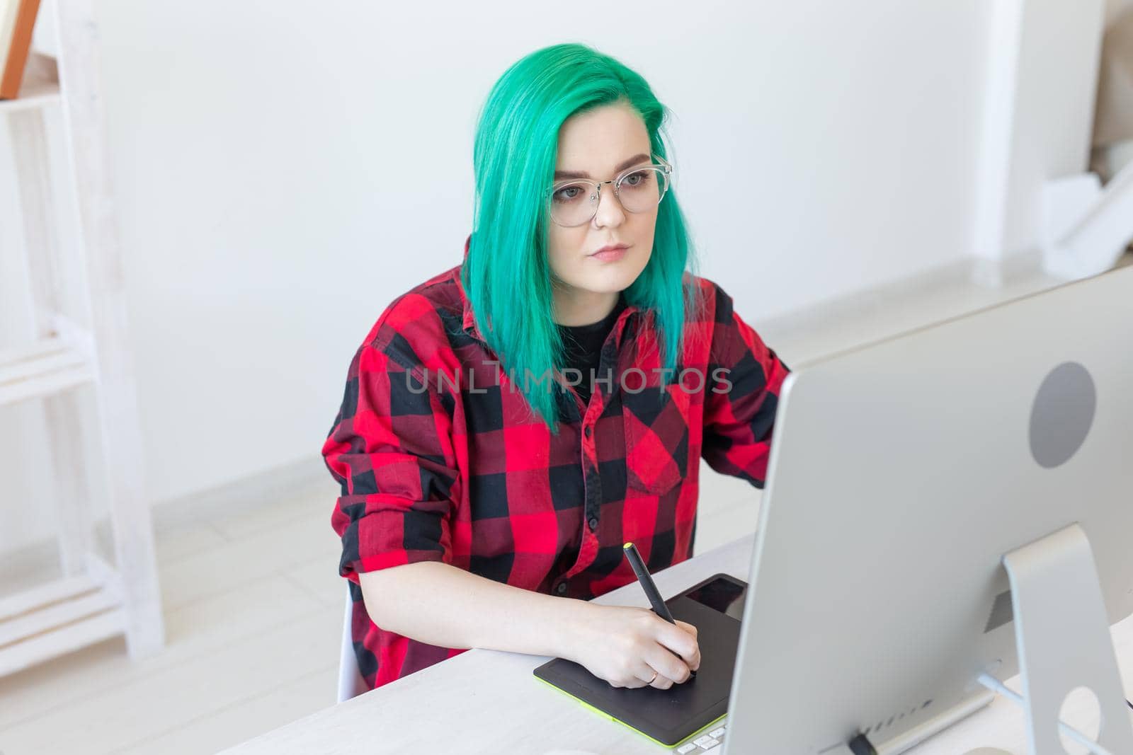 Graphic designer, people concept - Young designer female hipster with graphic tablet working in office.